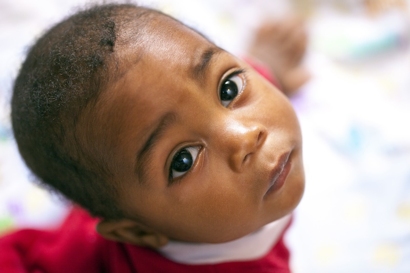 african american toddler wearing a read shirt looking up at the camera